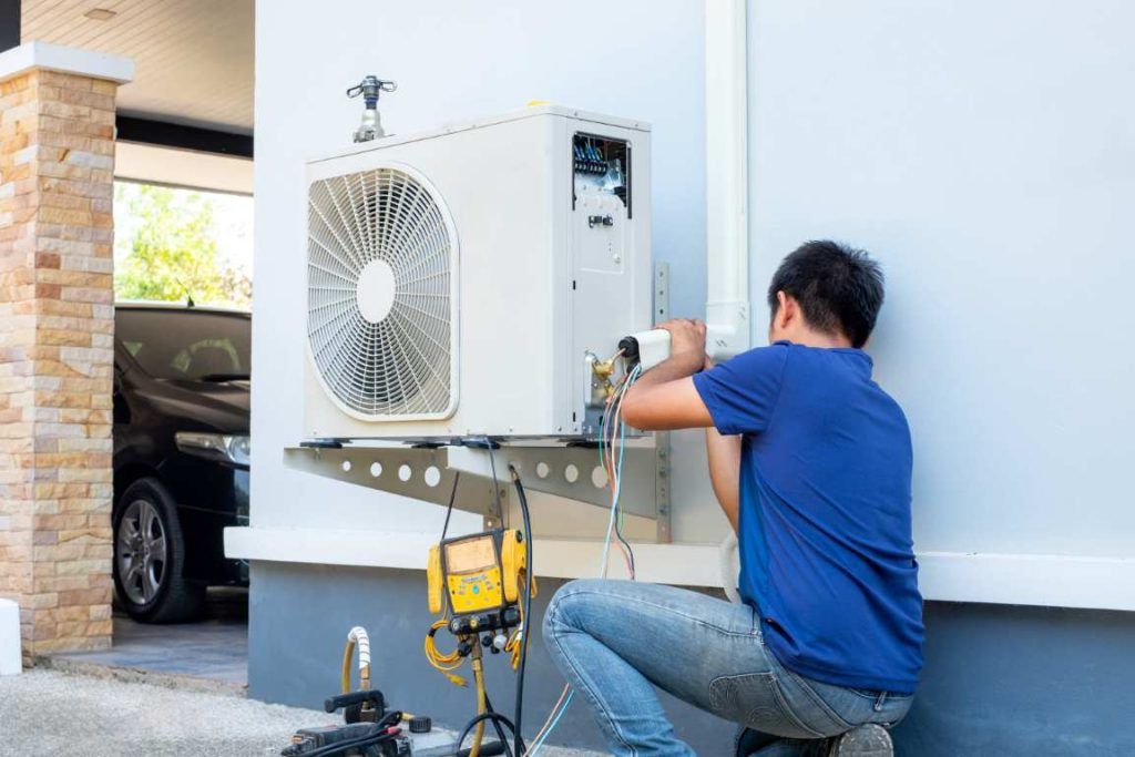 Male Technician Installing Outdoor Unit Of Air Conditioner To Cool The Household