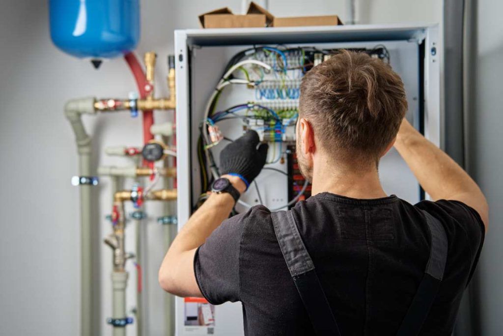 Technician Working On Internal Wiring Of Heat Pump, Inspecting Electrical Connections.