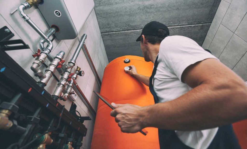 The Technician Checking The Heating System In The Boiler Room With Tablet In Hand